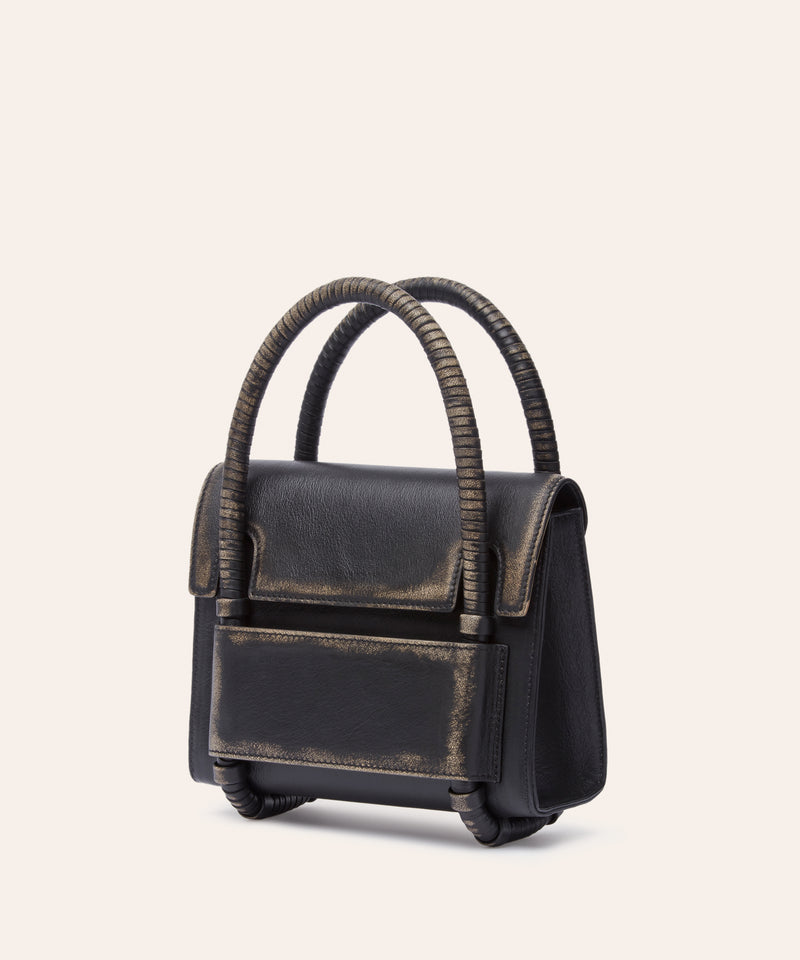 KUN HONG Black handbag with leather wrapped double handle on a beige background