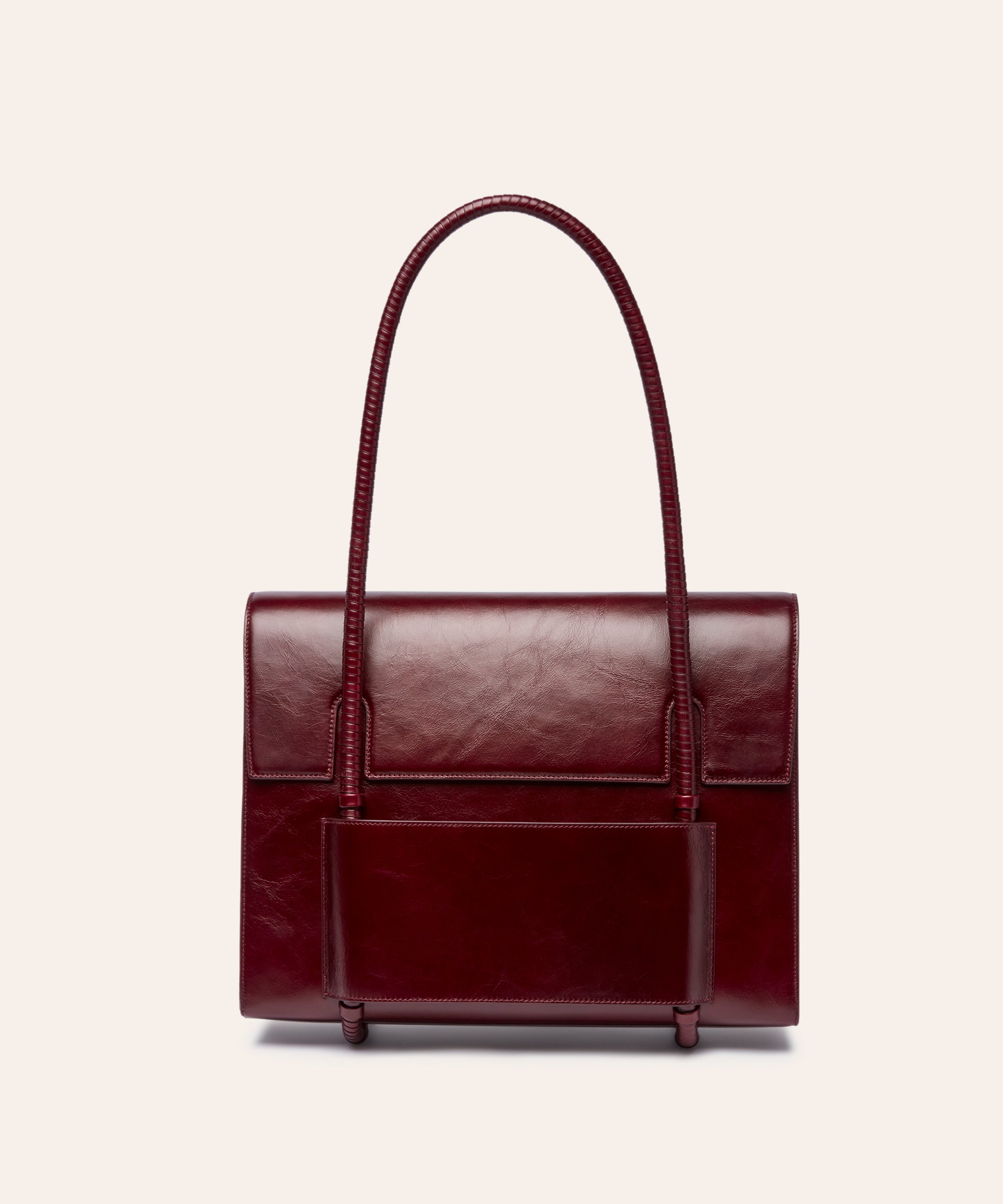 KUN HONG MOTHER SATCHEL LACQUER RED BURGUNDY Maroon handbag with leather wrapped double handle on a beige background