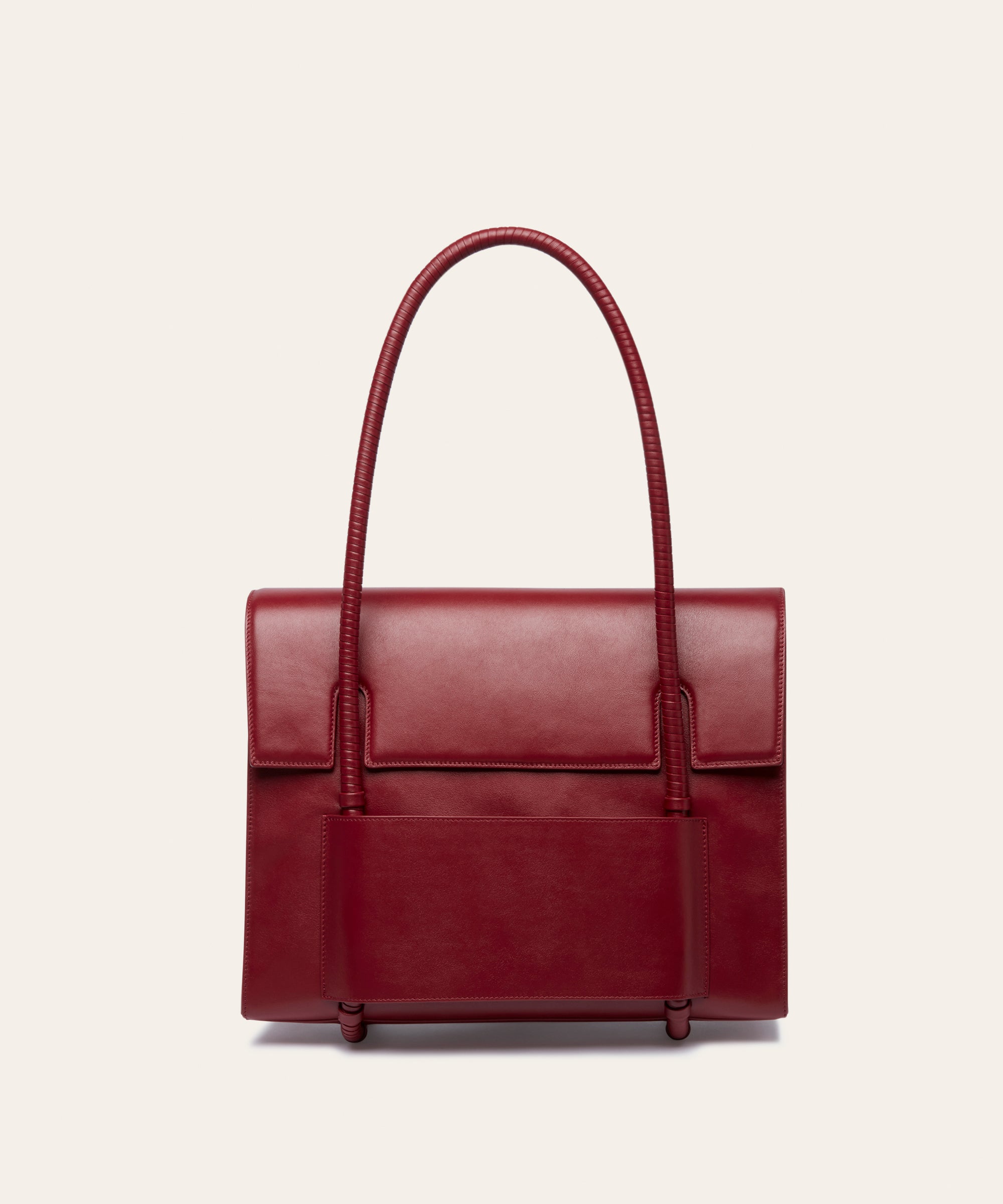 KUN HONG CHUA MOTHER SATCHEL in HÓNG (2022) by Xiao Han and Kun Hong  Red handbag with leather wrapped handle on a beige background