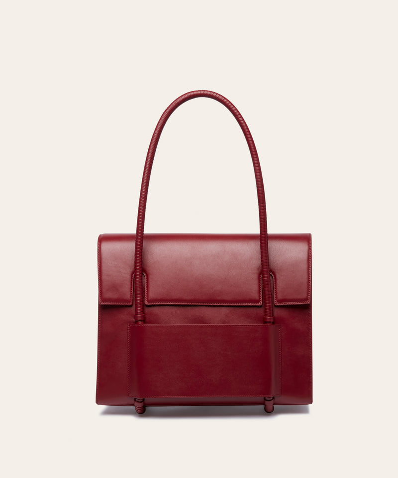 KUN HONG CHUA MOTHER SATCHEL in HÓNG (2022) by Xiao Han and Kun Hong  Red handbag with leather wrapped handle on a beige background