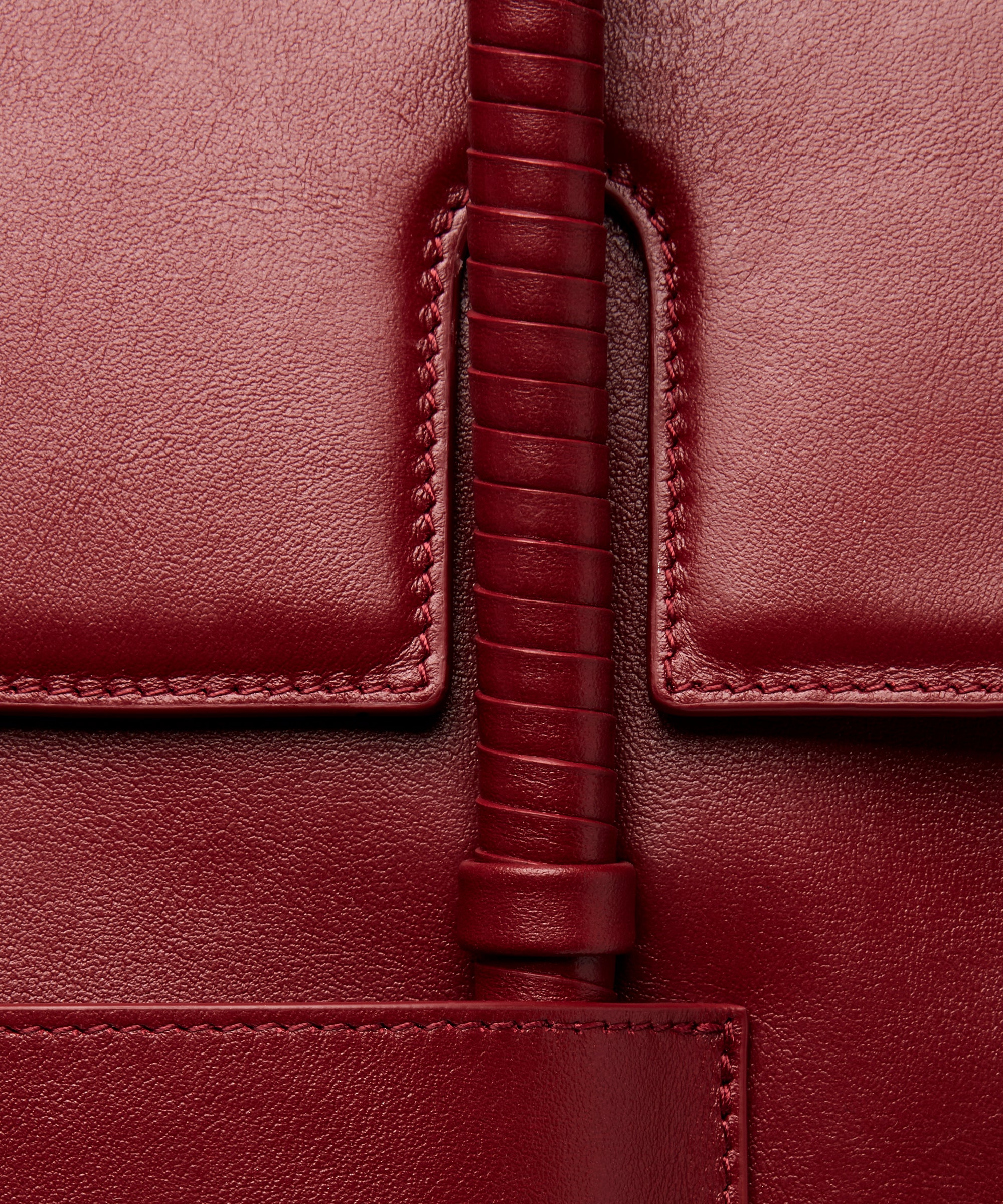 KUN HONG CHUA MOTHER SATCHEL in HÓNG (2022) by Xiao Han and Kun Hong Close-up of a burgundy leather bag with wrapped handle and stitching detail
