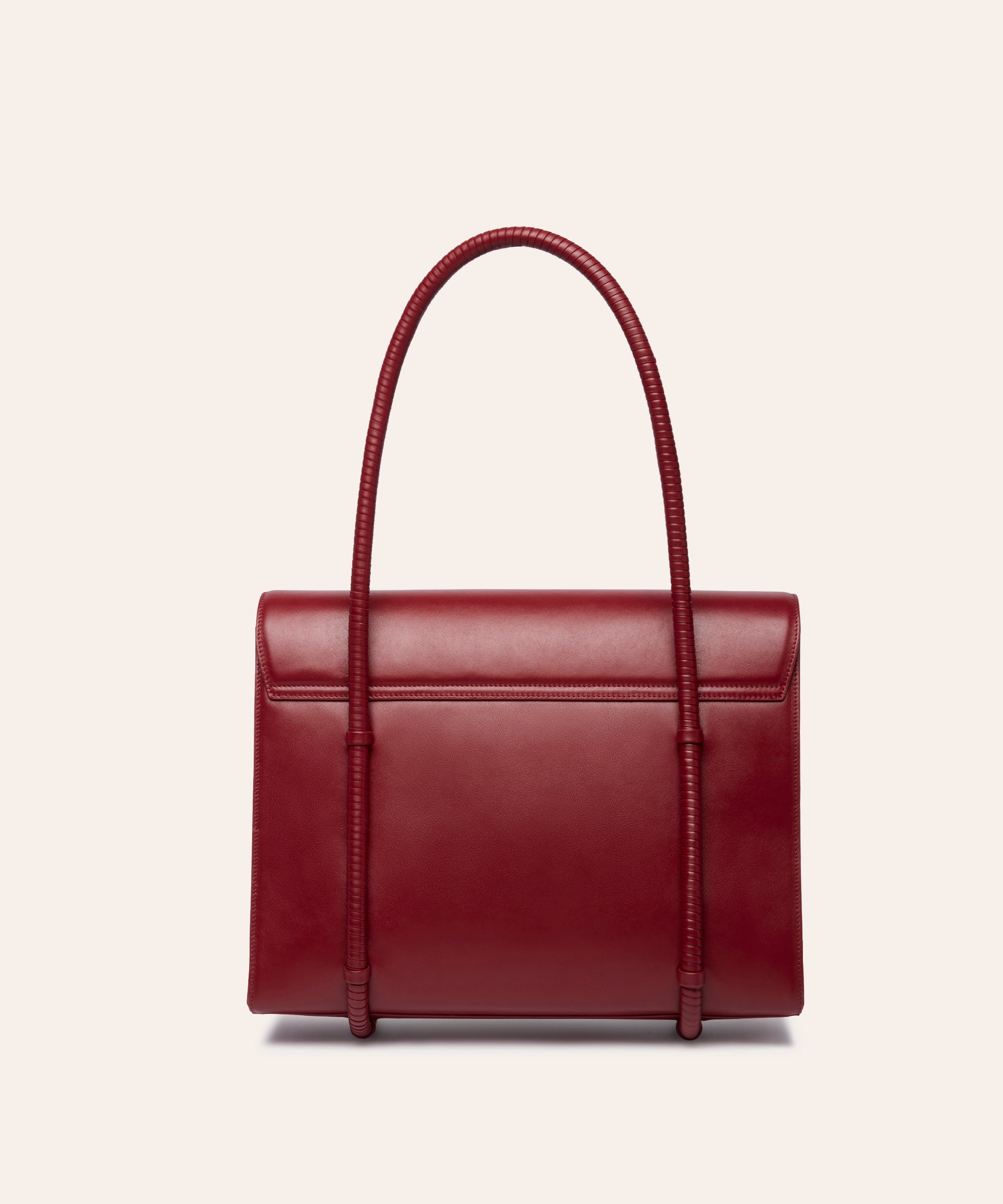 KUN HONG CHUA MOTHER SATCHEL in HÓNG (2022) by Xiao Han and Kun Hong Red handbag with a textured handle on a light beige background