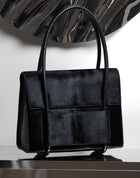 KUN HONG CHUA BAG CHUA MOTHER SATCHEL in BLACK FUZZ Black handbag on a reflective surface with a white background