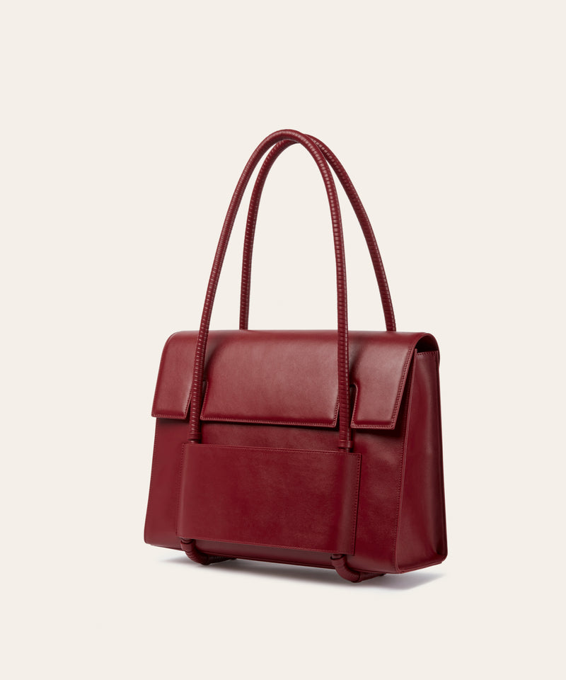 KUN HONG CHUA MOTHER SATCHEL in HÓNG (2022) by Xiao Han and Kun Hong Red handbag on a light beige background
