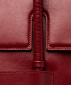 KUN HONG CHUA MOTHER SATCHEL in HÓNG (2022) by Xiao Han and Kun Hong Close-up of a burgundy leather bag with wrapped handle and stitching detail