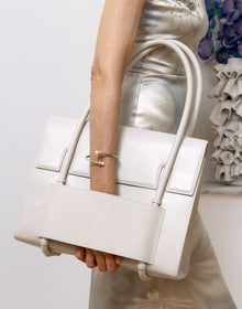KUN HONG CHUA BAG White KUN HONG CHUA Mother Satchel handbag held by a person wearing a light-colored dress against a neutral background